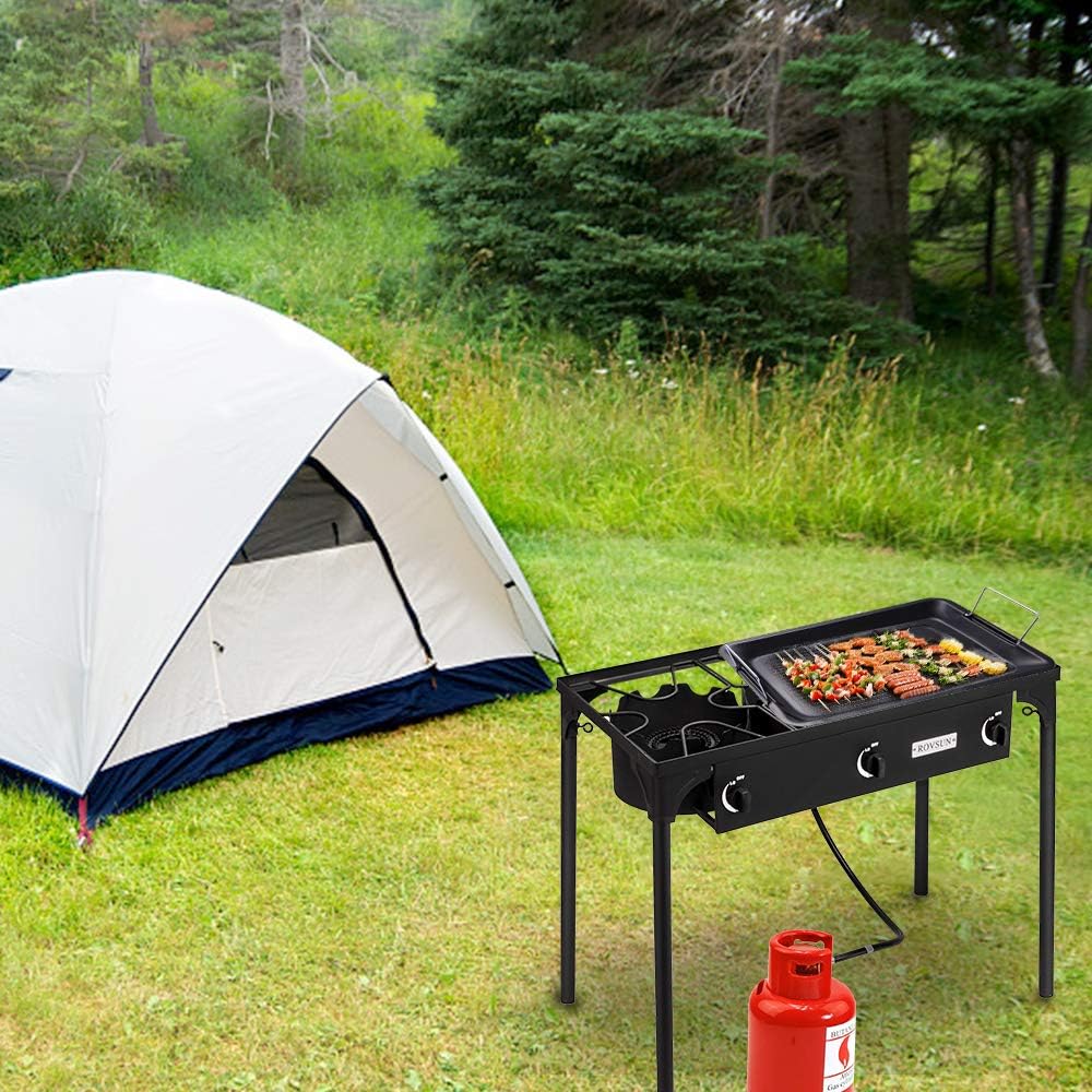 Camping scene with a tent and portable grill in a grassy area.