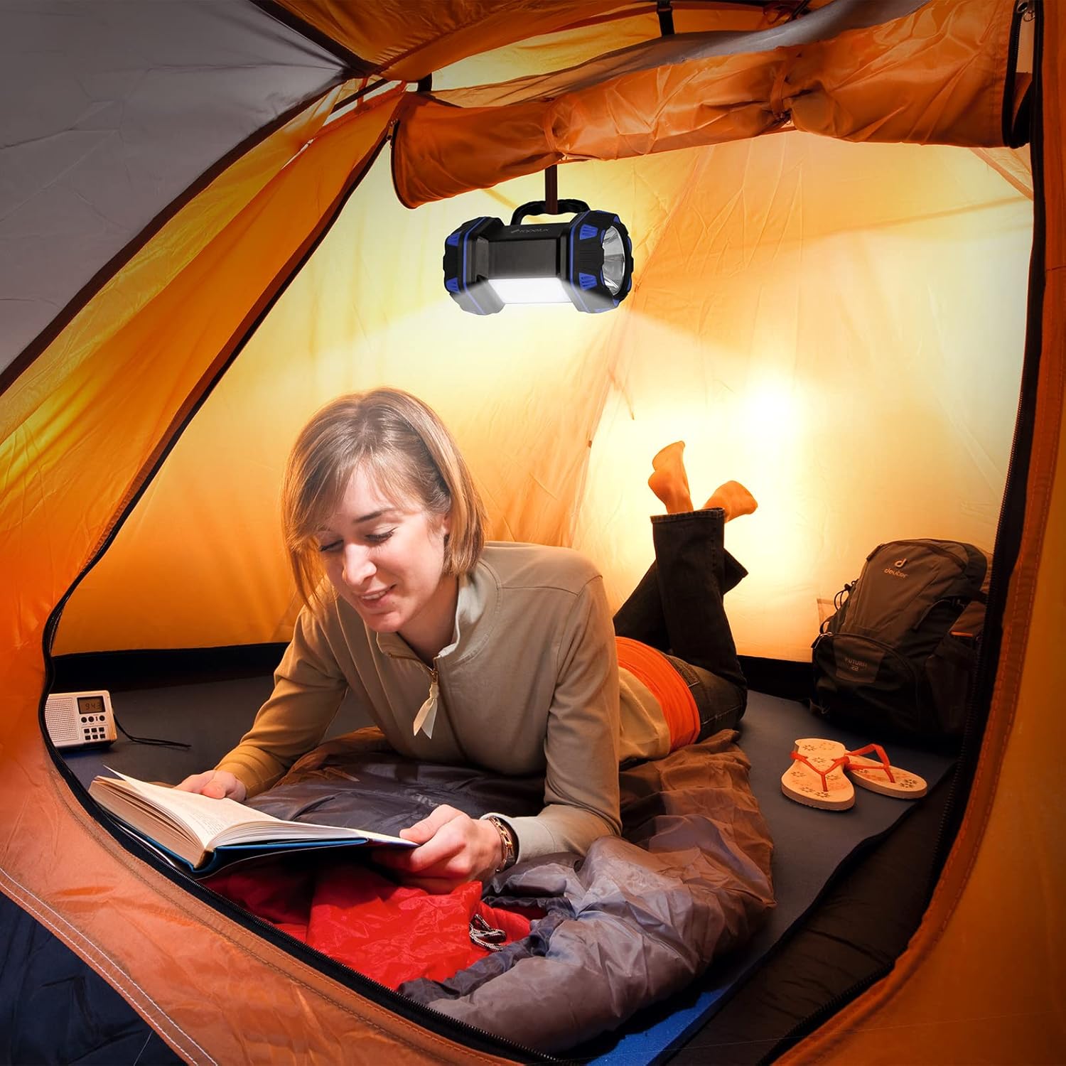 Person reading a book inside a tent with camping gear around