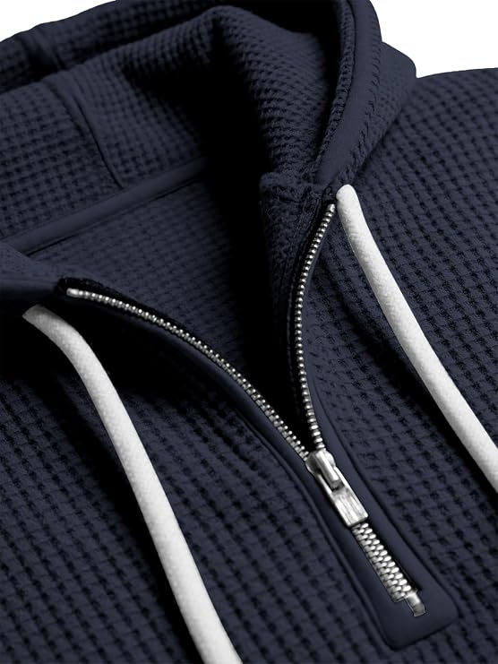 Close-up of a navy blue textured hoodie with a zipper and white drawstrings on a light gray background.