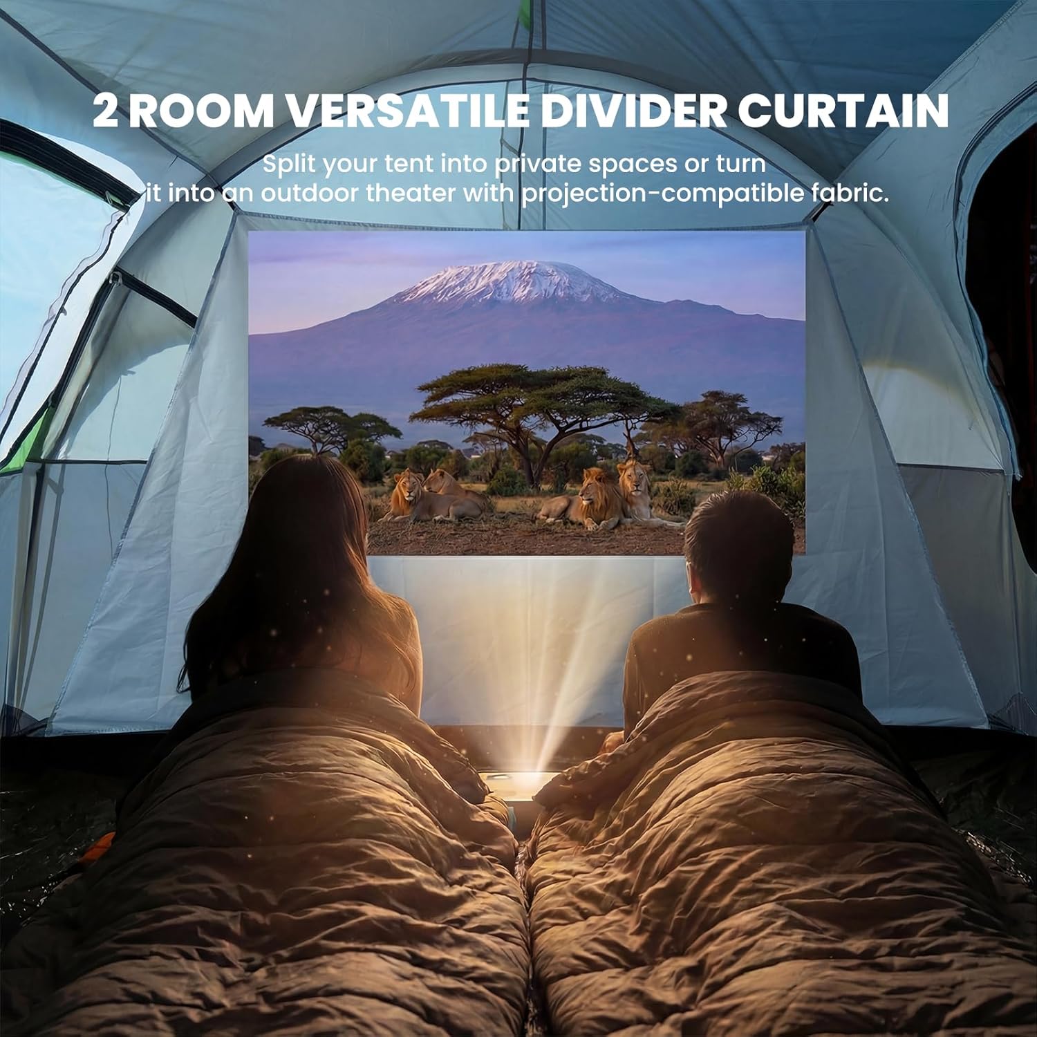 Two people sitting inside a tent with a 2-room versatile divider curtain, watching a projection of lions and a mountain.