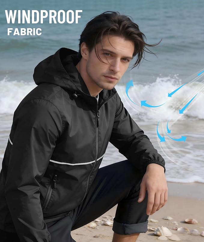 Man wearing a black windproof jacket on a beach with ocean waves in the background