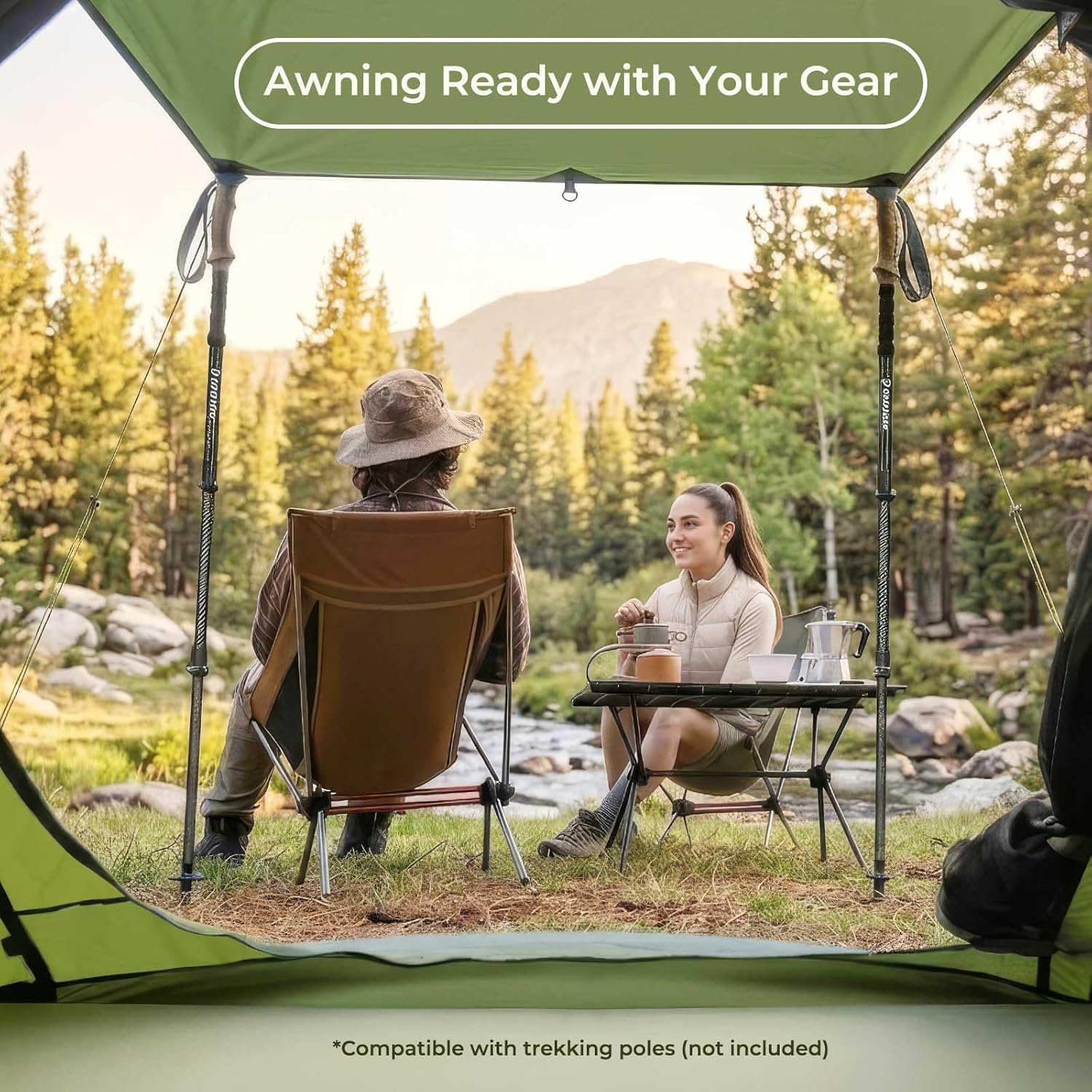 Two people sitting under a green camping awning in a forest setting.