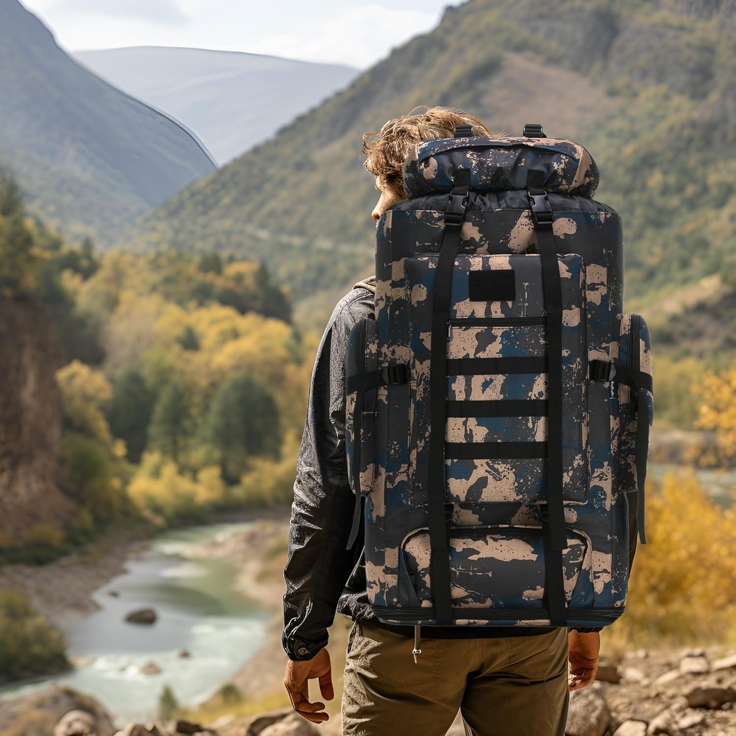Hiker wearing the 100L blue and black rucksack on a mountain trail for a multi-day expedition.