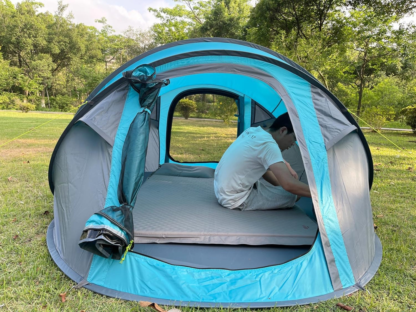 Person inside a blue and gray tent in a grassy outdoor area