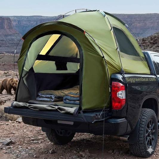 Green tent attached to a black truck in a desert landscape with a bear in the background. Big Green Bear
