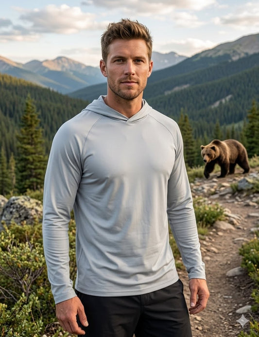 Man in a gray hoodie standing on a mountain path with a bear in the background Biggreenbear.com