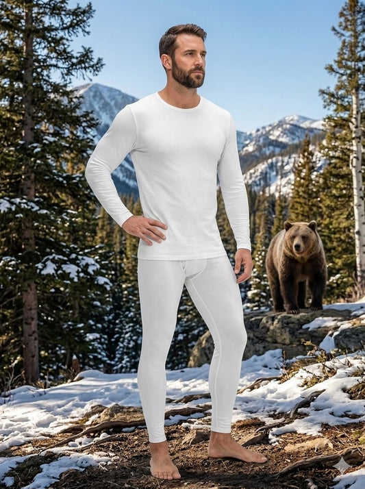 Man wearing white thermal underwear standing in a snowy forest with a bear in the background big gree bear