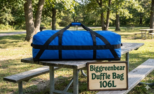 Blue duffel bag with black straps on a wooden picnic table in a park setting, featuring 'Biggreenbear Duffle Bag 106L' sign.