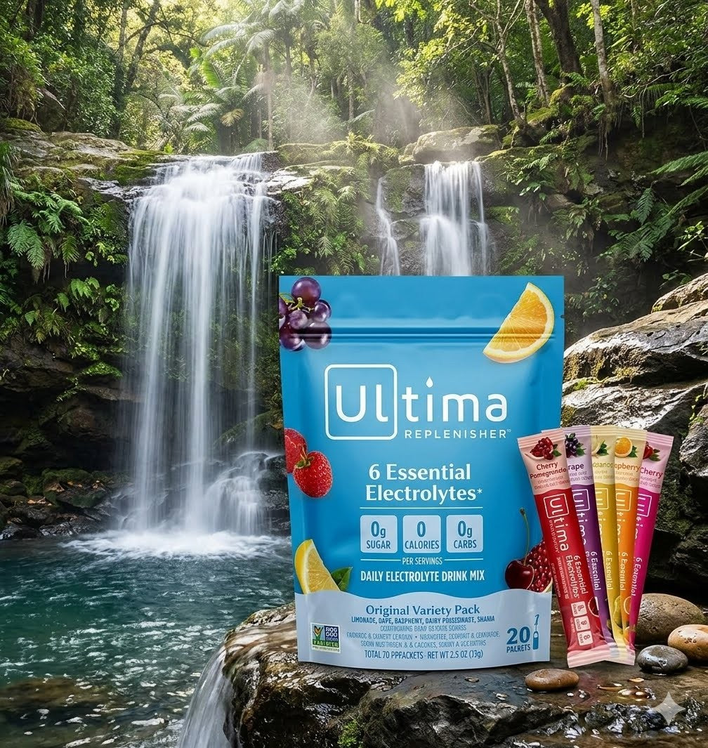 Ultima Replenisher electrolyte drink mix pouch and individual stick packs displayed in front of a lush waterfall forest scene. The blue pouch reads 'Ultima Replenisher 6 Essential Electrolytes' and includes fruit and citrus graphics, with four colorful stick packs standing beside it on rocks by the water.