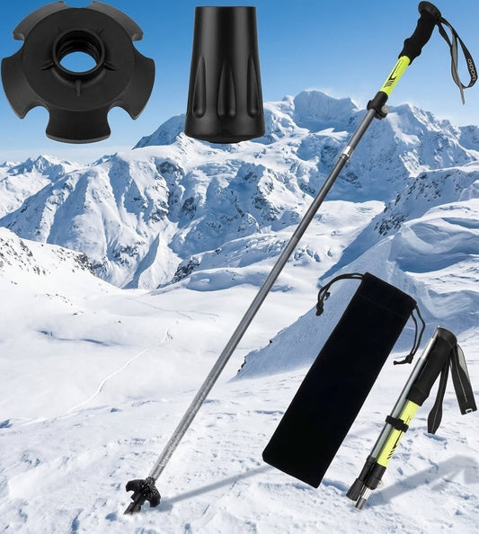 A pair of black and yellow trekking poles displayed with a black carrying pouch, an extra black rubber tip, and a second tip on a snowy mountain background.