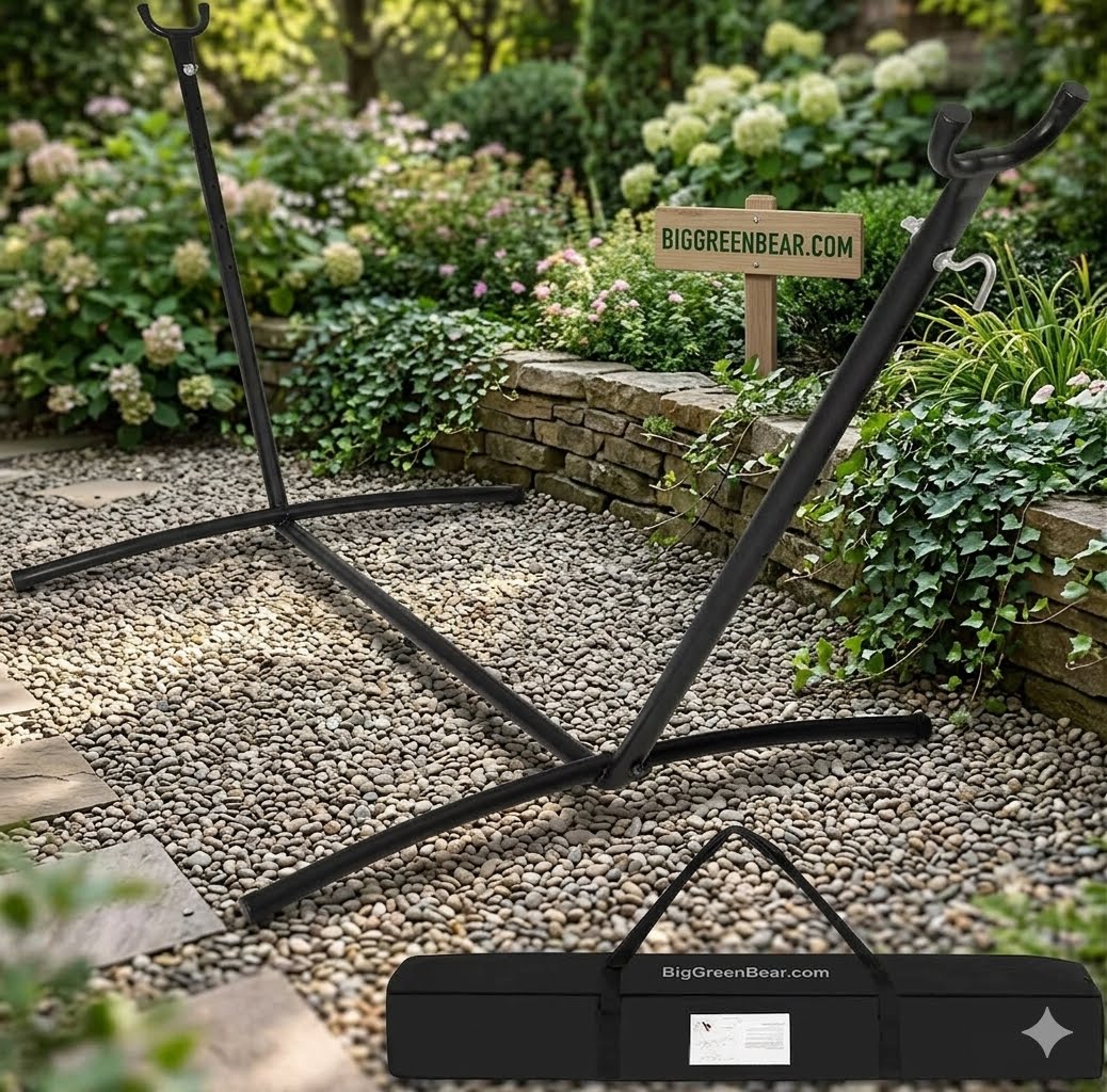 A black metal outdoor swing stand displayed on a gravel path in a landscaped garden, with its carrying case shown in the foreground and a sign reading BIGGREENBEAR.COM in the background.