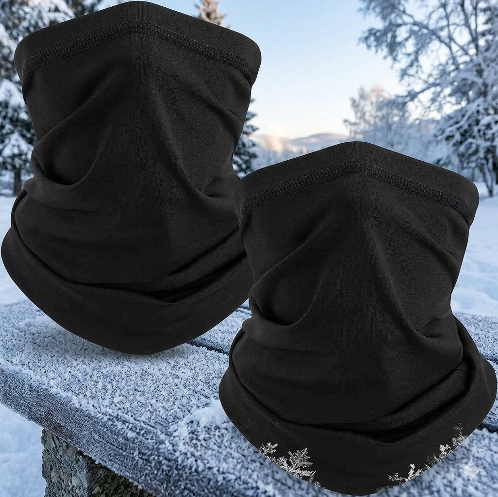 Two black fleece face masks or neck gaiters displayed outdoors on a snow-covered stone ledge, with a snowy forest background. big green bear biggreenbear.com