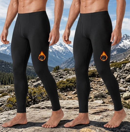 Two cropped male models standing outdoors on a rocky mountain landscape, wearing black full-length compression-style leggings with a small orange and yellow flame graphic on the upper thigh. big green bear biggreenbear.com
