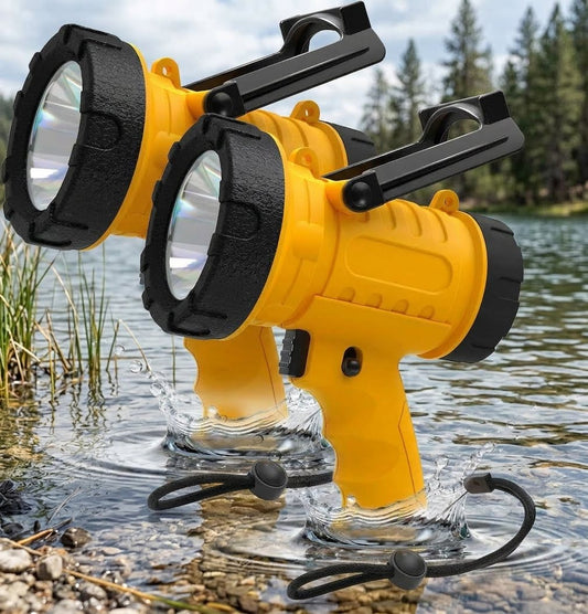 Two yellow and black waterproof tactical flashlights standing in shallow water outdoors, with trees and rocks visible in the background. big green bear biggreenbear.com