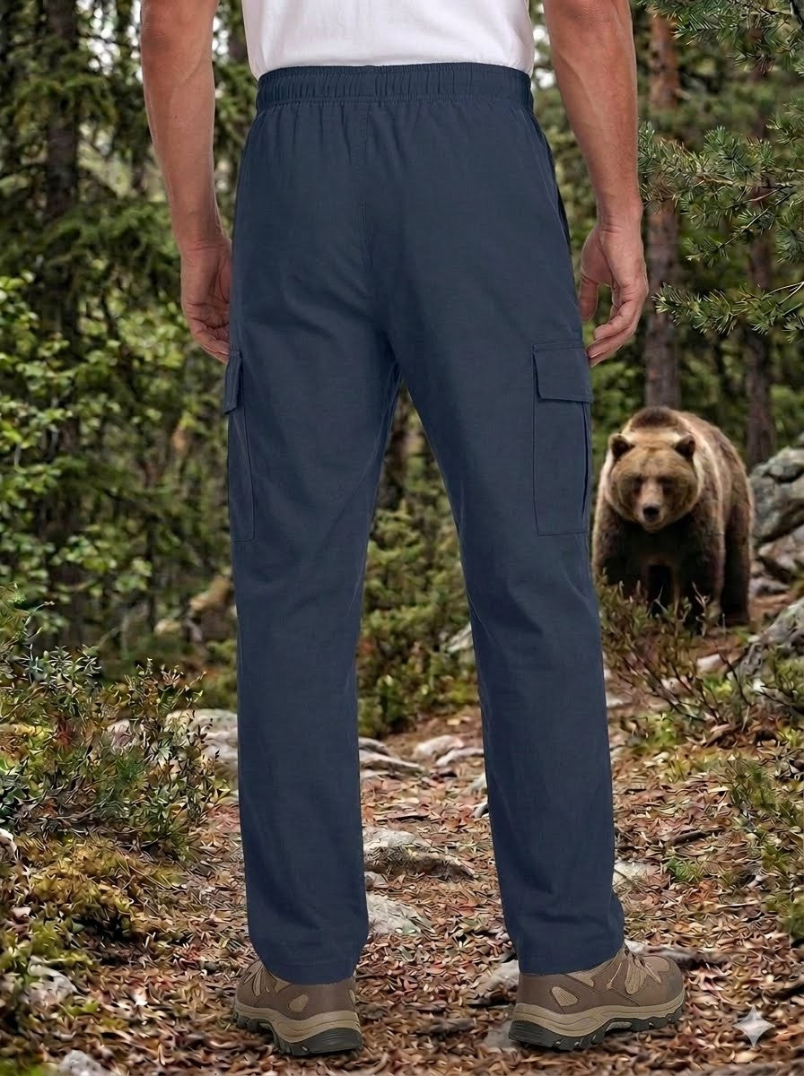 Person wearing navy cargo pants in a forest with a bear in the background