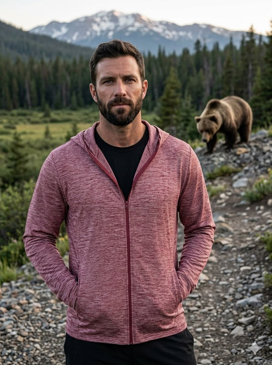 Man in a pink hoodie standing in a forest with a bear in the background Big Green Bear