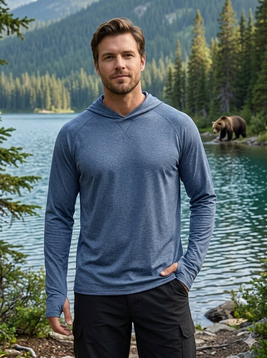 Man wearing a blue hoodie standing in front of a lake with a bear in the background big green bear