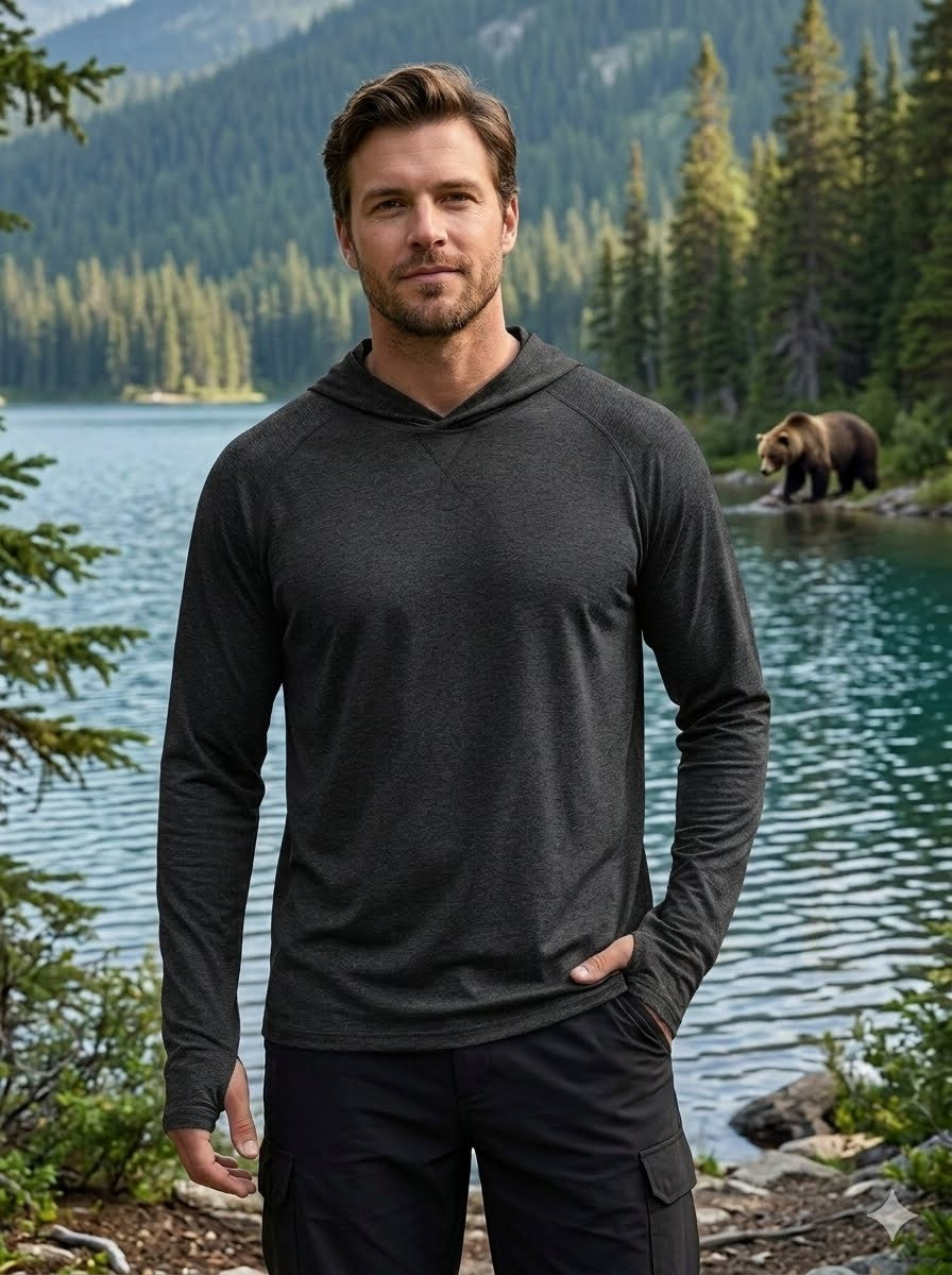 Man wearing a dark gray hoodie standing in front of a lake with a bear in the background big green bear