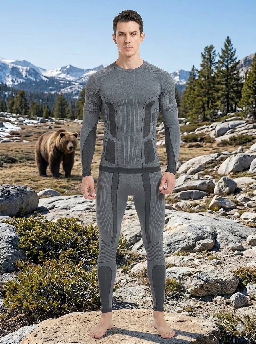 Person wearing a gray compression suit in a mountainous landscape with a bear in the background.