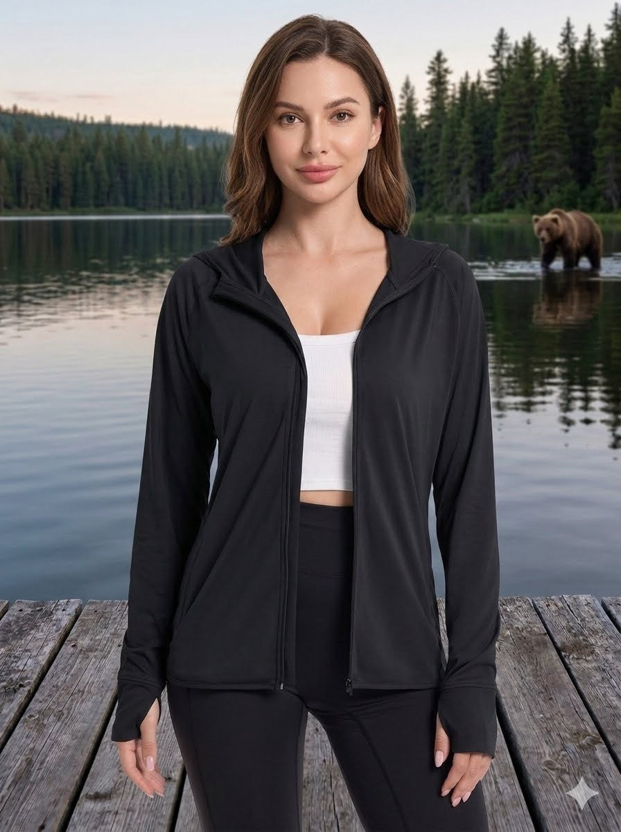 Woman in black jacket and white top standing on a wooden dock with a lake and bear in the background big green bear