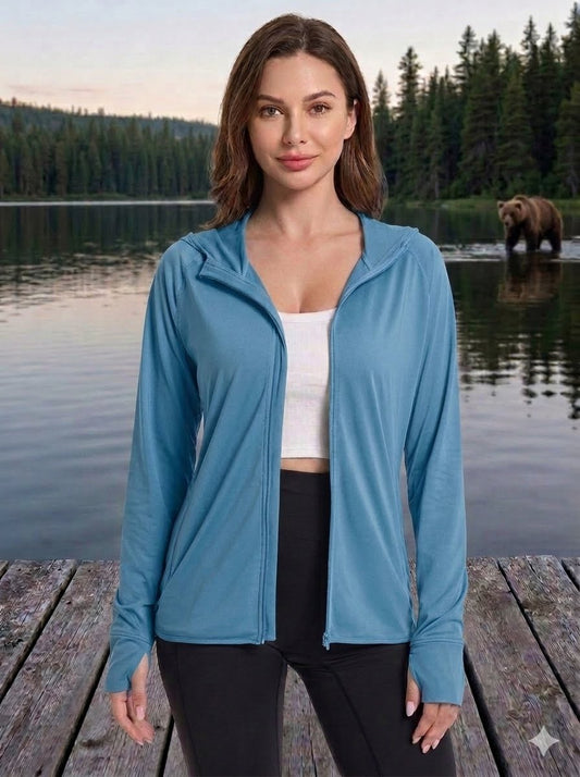 Woman wearing a blue jacket standing on a dock with a lake and bear in the background big green bear
