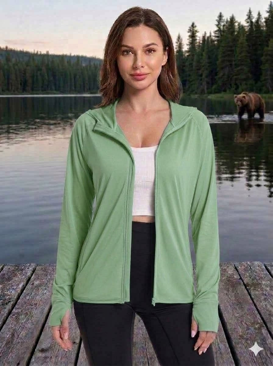 Woman wearing a green jacket by a lake with a bear in the background big green bear