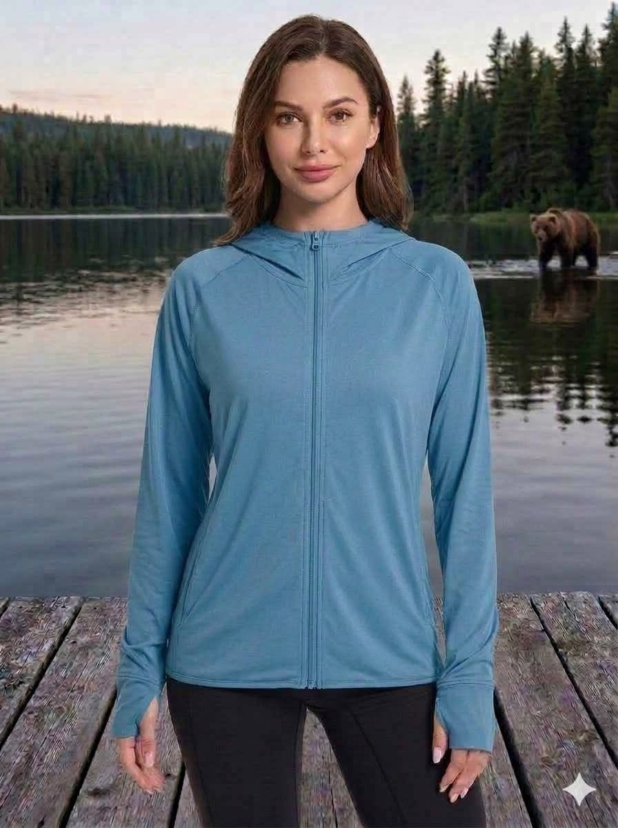 Woman wearing a blue jacket standing on a wooden dock with a bear in the background.