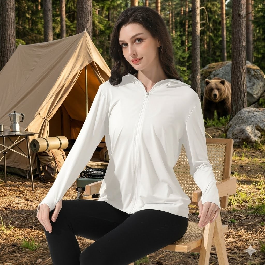 Woman in a white jacket sitting outdoors with a tent and bear in the background