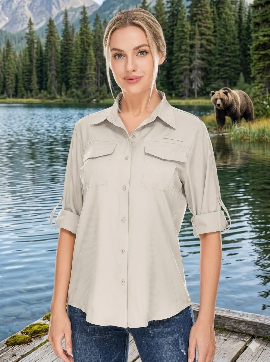 Woman wearing a beige shirt standing by a lake with a bear in the background