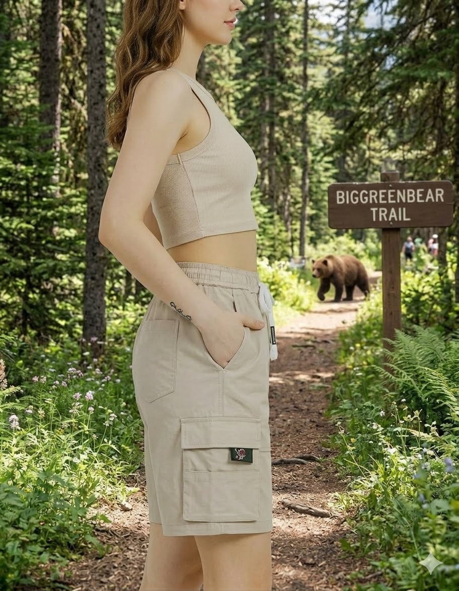 Woman in beige outfit standing on a trail with a bear and sign in the background