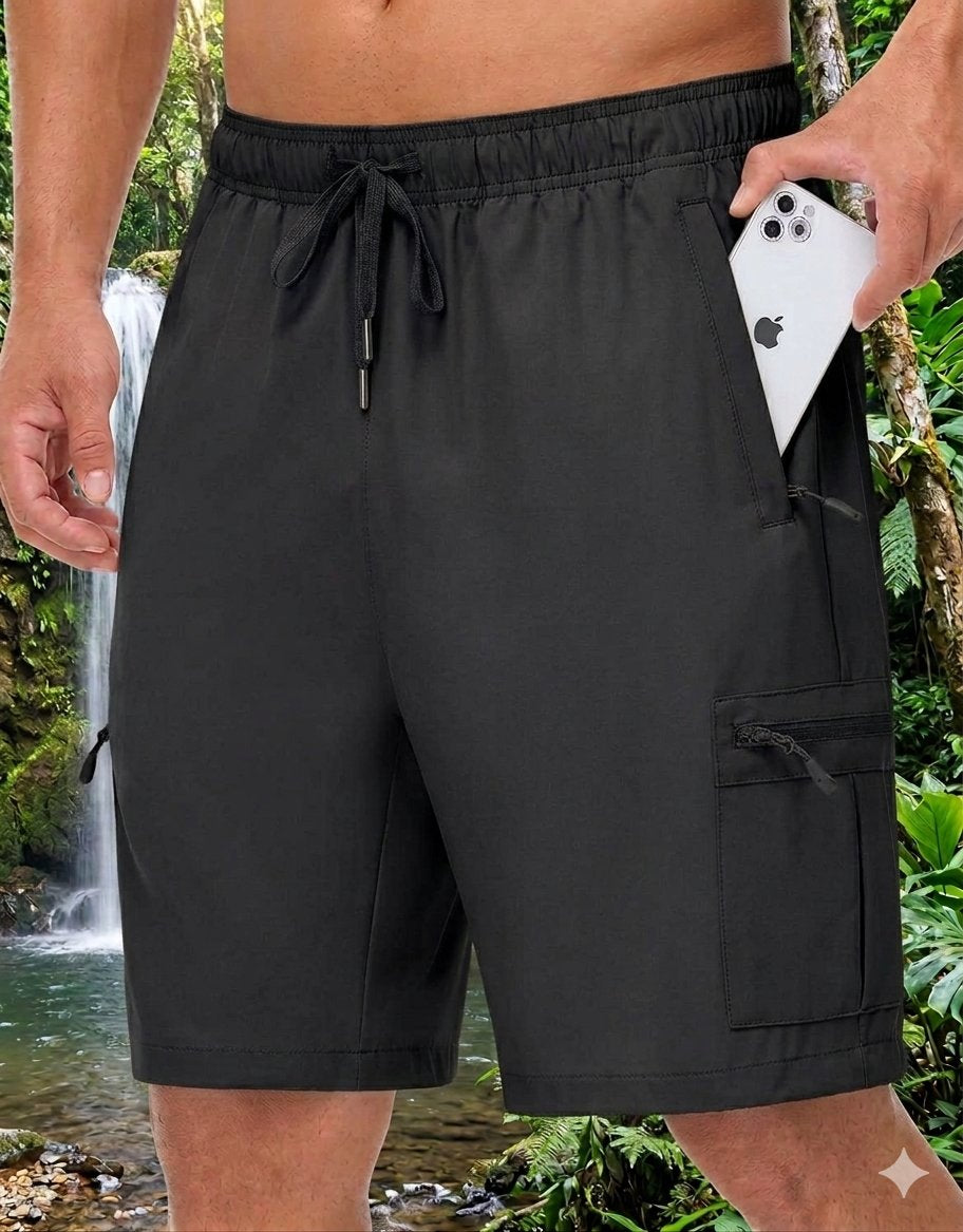 Black men's swim trunks with an elastic drawstring waist and side cargo pockets, shown on a model in a tropical outdoor setting with a waterfall in the background.