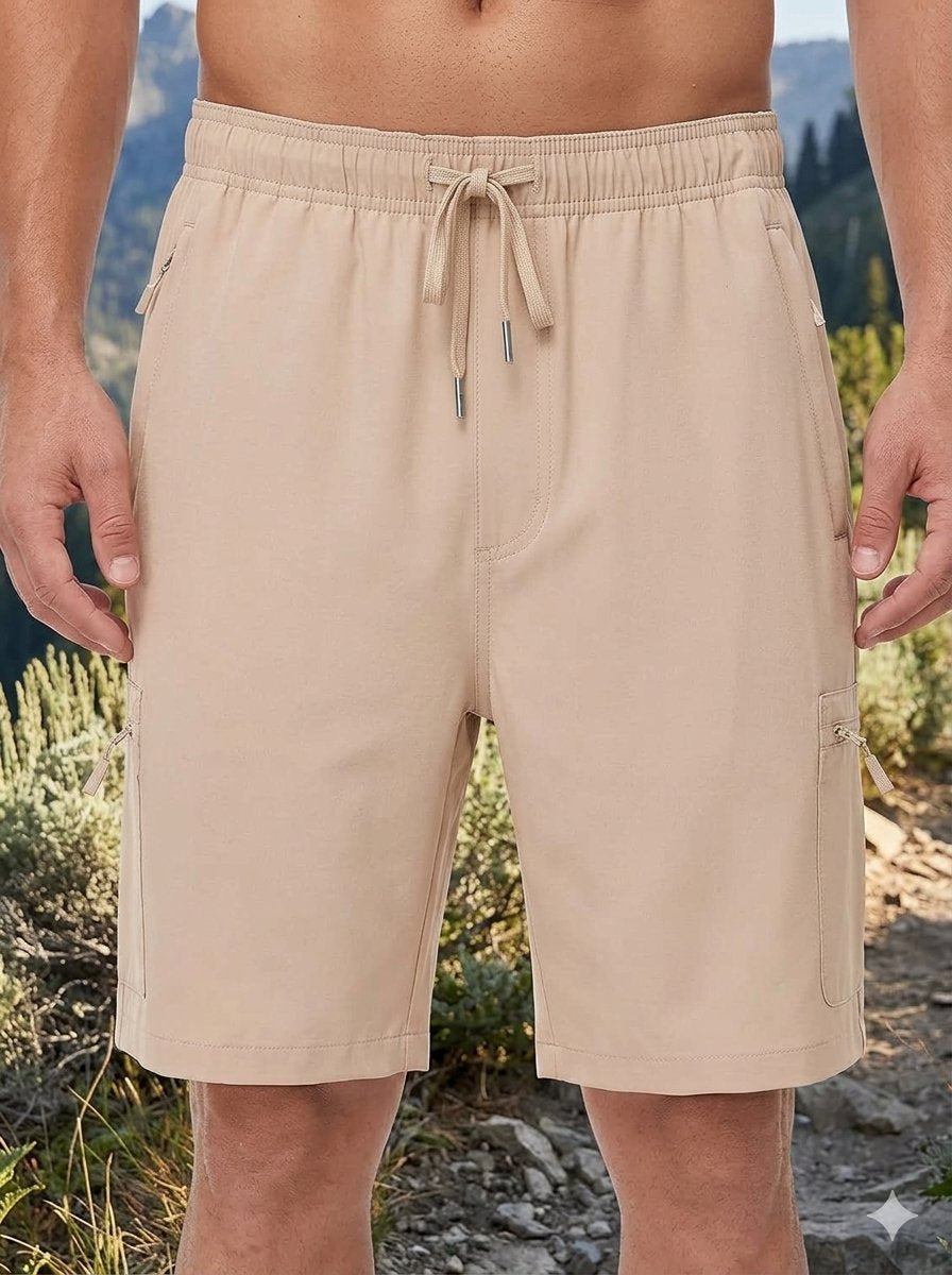 Beige men's cargo shorts with an elastic drawstring waist, worn by a model in an outdoor mountain setting.