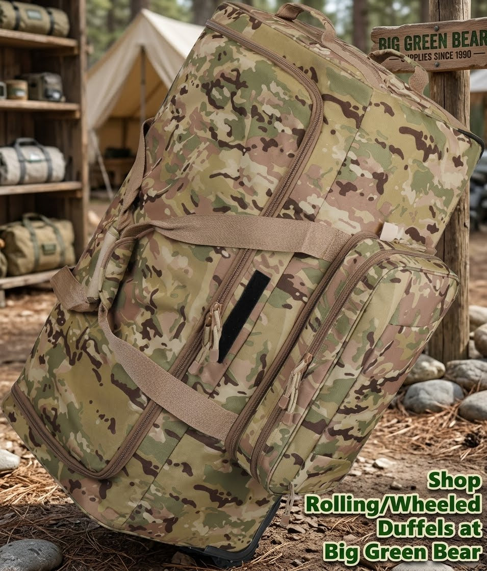 A large rolling duffel bag in a woodland camouflage pattern is shown outdoors on a forest floor with trees, rocks, and a tent in the background. A wooden sign reads Big Green Bear, and text in the lower right says Shop Rolling/Wheeled Duffels at Big Green Bear.