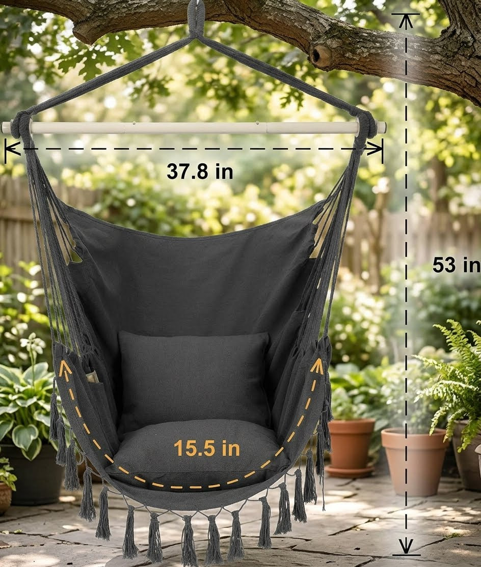 A dark gray fabric hanging hammock chair with tassels and a matching cushion, suspended from a tree branch in a garden patio setting. White dashed lines and text show dimensions: 37.