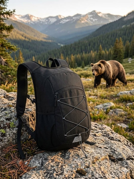 "Front view of 15L ultra-light black daypack with reflective bungee cords on a rocky mountain trail." Big Green Bear
