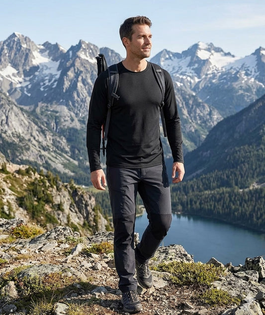 Man with a backpack standing on a mountain peak with a scenic view of mountains and a lake. Big Green Bear