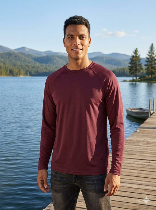 Man wearing a maroon long-sleeve shirt standing on a dock by a lake with mountains in the background. Big Green Bear