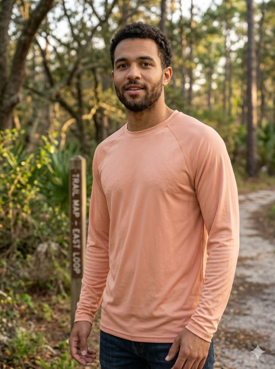 Man wearing a peach long-sleeve shirt standing on a trail with trees in the background Biggreenbear.com