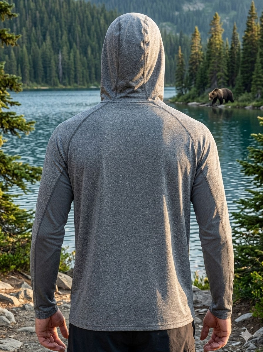 Person wearing a gray hoodie standing by a lake with a bear in the background