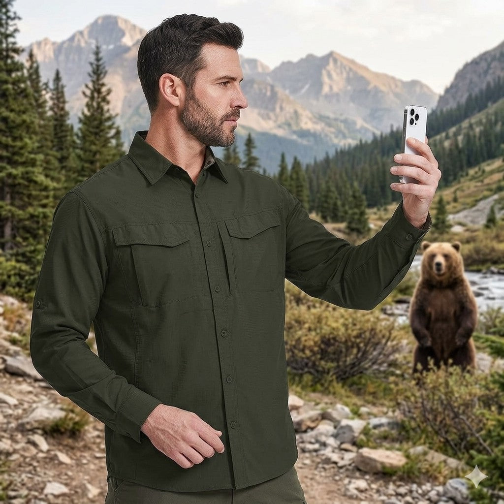 Man taking a selfie with a bear in the background in a mountainous forest setting