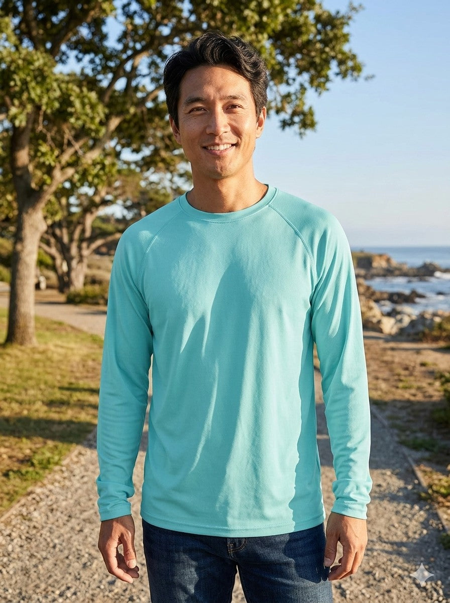 Man wearing a light blue long-sleeve shirt standing outdoors with trees and ocean in the background