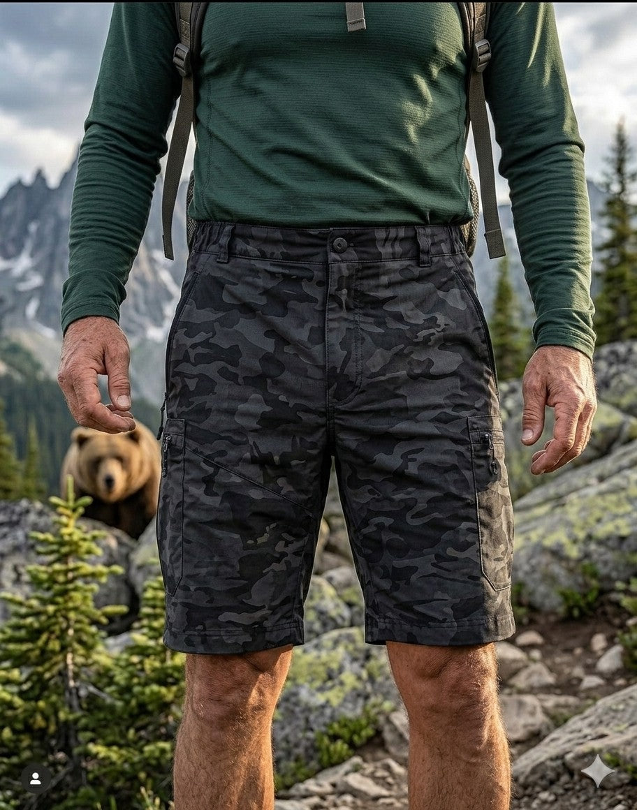 Front view of Big Green Bear Men's Black Camo Hiking Cargo Shorts on a hiker in a mountain setting with a bear in the background.