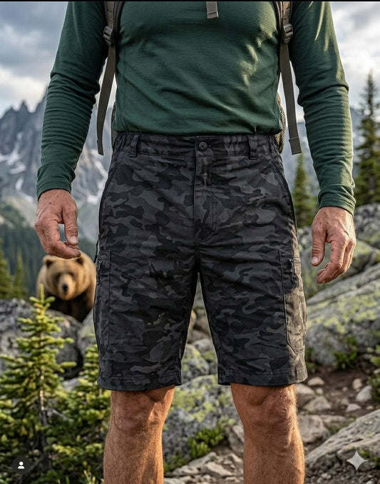 Front view of Big Green Bear Men's Black Camo Hiking Cargo Shorts on a hiker in a mountain setting with a bear in the background.
