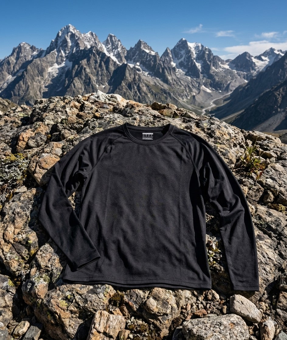 Black long-sleeve shirt on a rocky mountain top with snow-capped peaks in the background